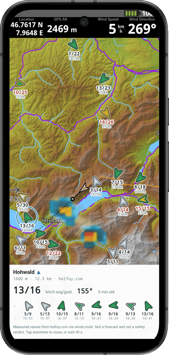 A phone running XCTrack. Wind arrows sit on the terrain around Interlaken, each labelled with speed, gust and station altitude, and a panel at the bottom shows one station's last few hours.
